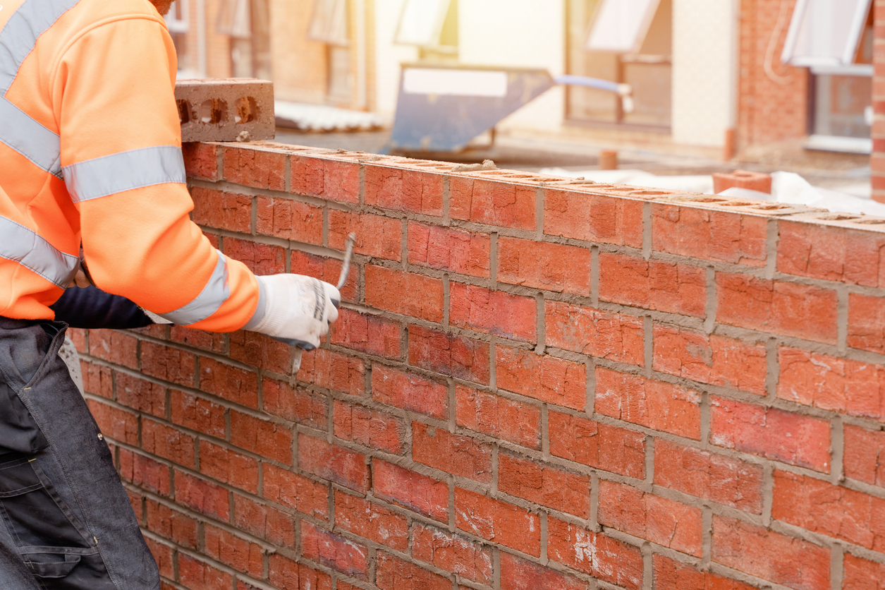 Man laying brick to make a wall