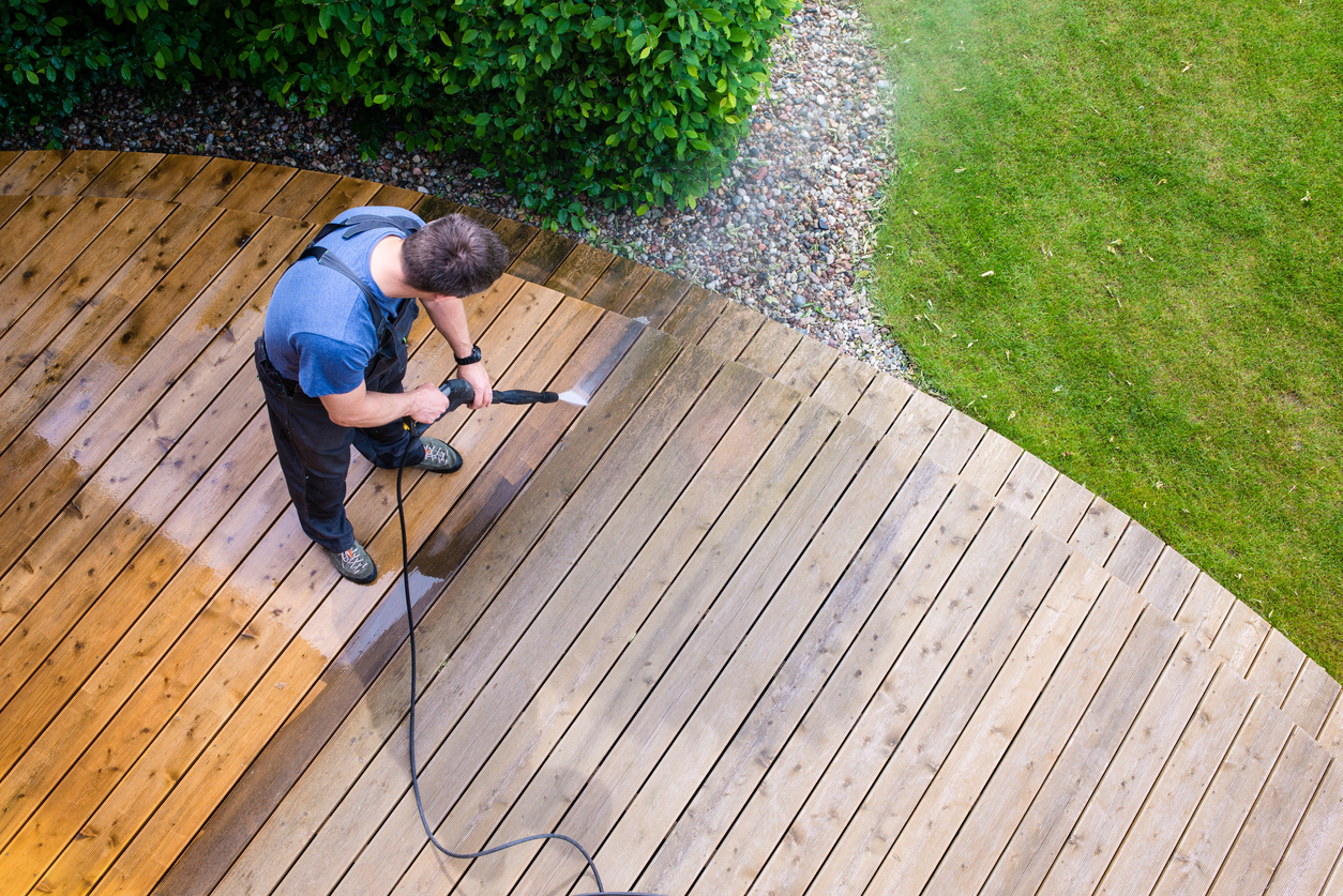 Man power washing his wooden deck