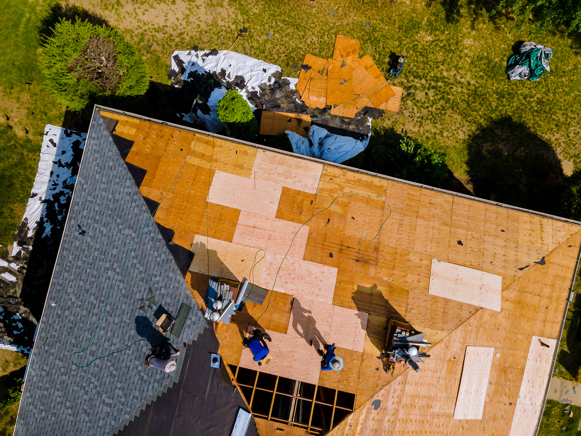 Group of men installing shingles on the roof of a house