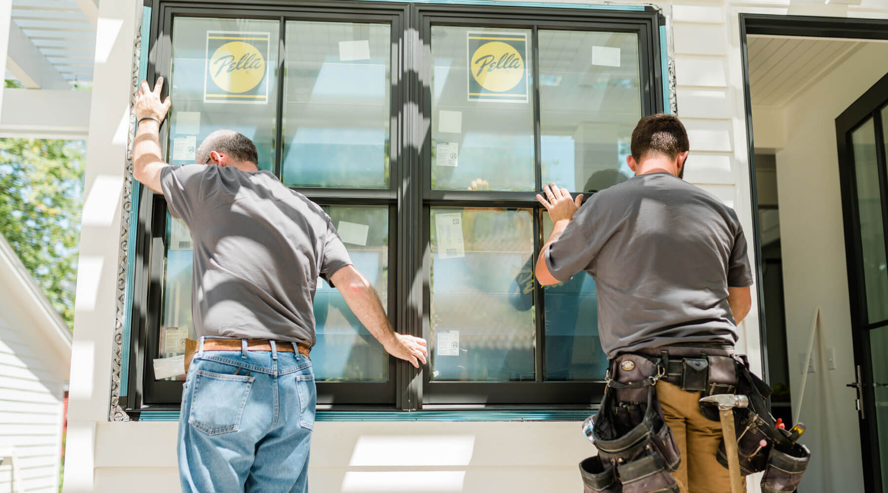 Two men installing large window and window frame